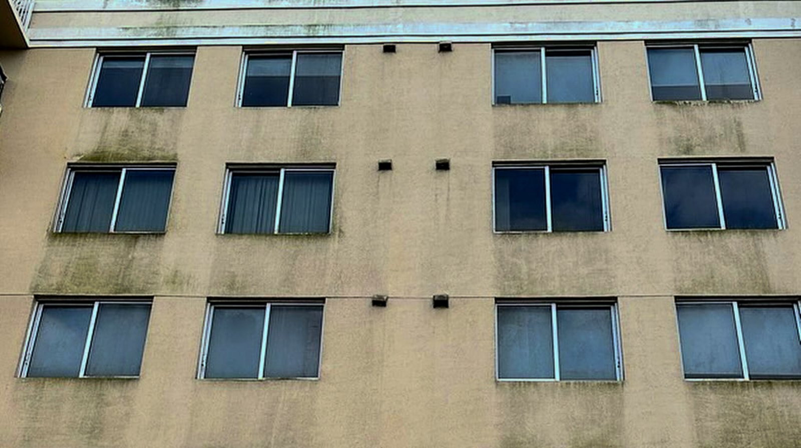 Mildew-stained condo facade before drone cleaning