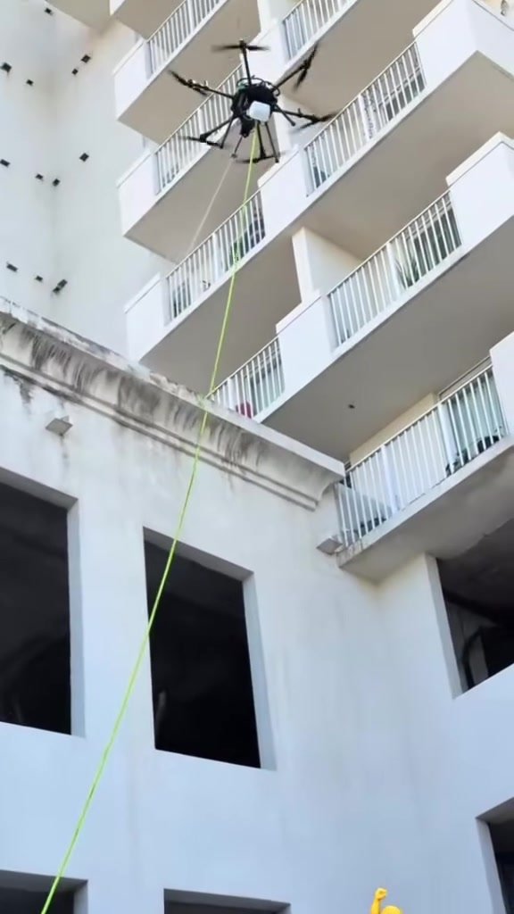 Drone washing a white condominium facade in South Florida